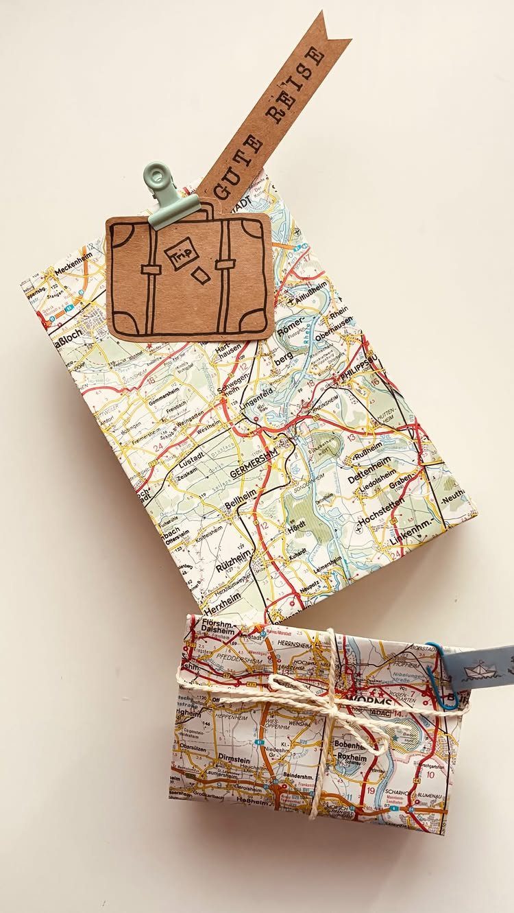 Gifts wrapped in recycled maps with a cardboard suitcase and white twine.