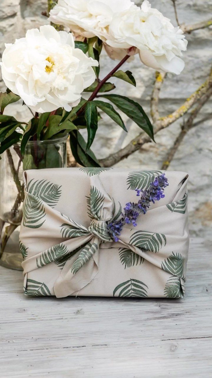 Gift wrapped in leaf-printed beige paper tied with a ribbon and lavender sprig.
