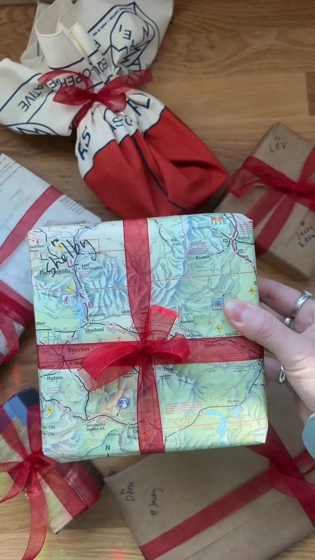 Gift wrapped in a vintage map with a red ribbon on wooden table