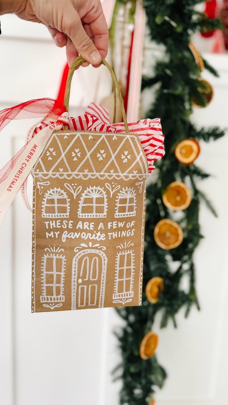 House-shaped brown paper gift bag with white drawings and red striped ribbon.