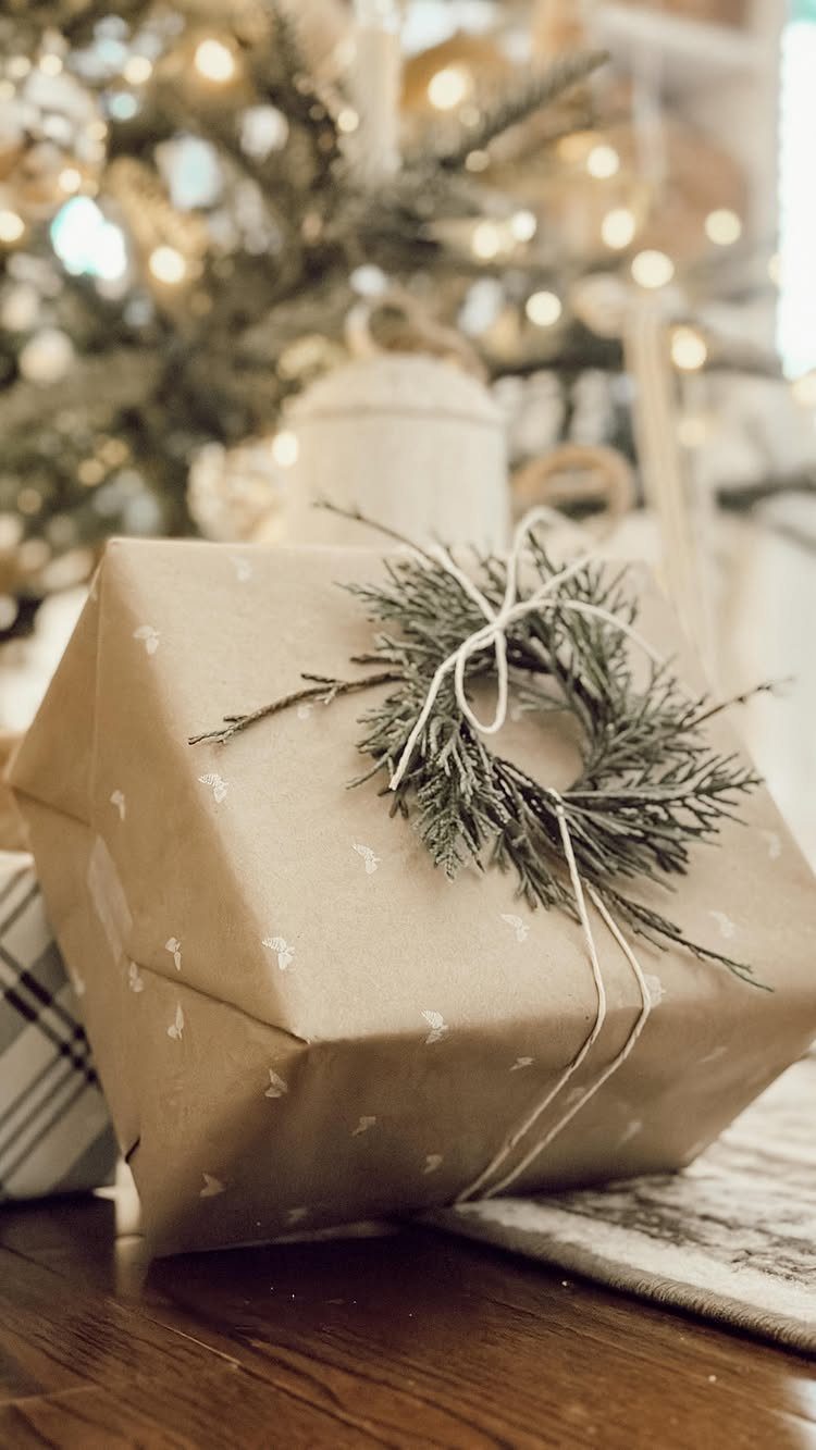 Brown paper wrapped gift with a small evergreen wreath tied with white twine.