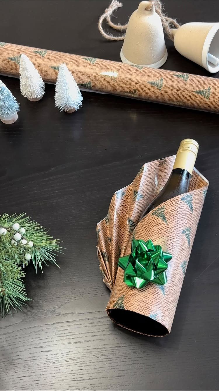 Wrapped wine bottle with a green bow on a dark wooden table