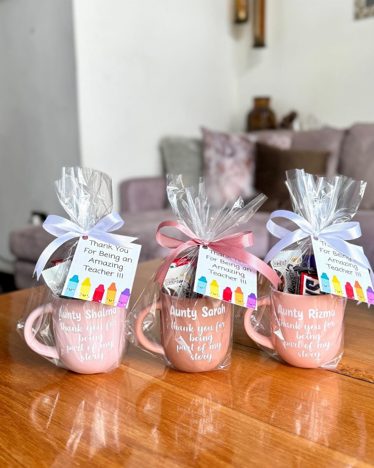Three pink gift mugs wrapped in cellophane with ribbons and thank you tags.