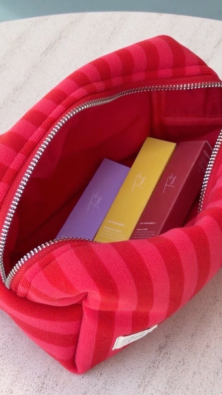 Red striped zippered pouch containing three colorful rectangular lip balm boxes.