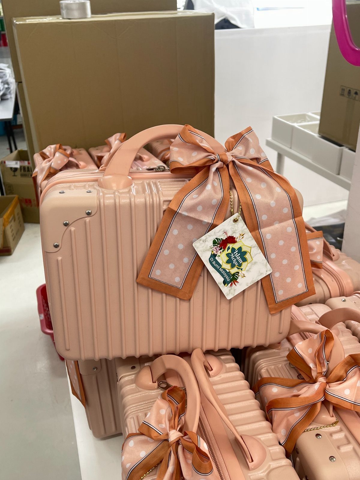 Peach-colored mini suitcases decorated with large satin bows and floral gift tags.