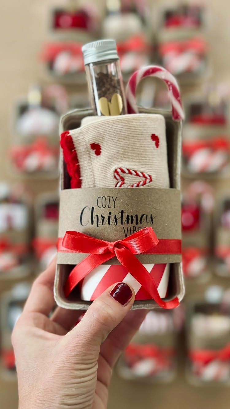 Christmas gift box with beige socks, a mini bottle, and a candy cane.