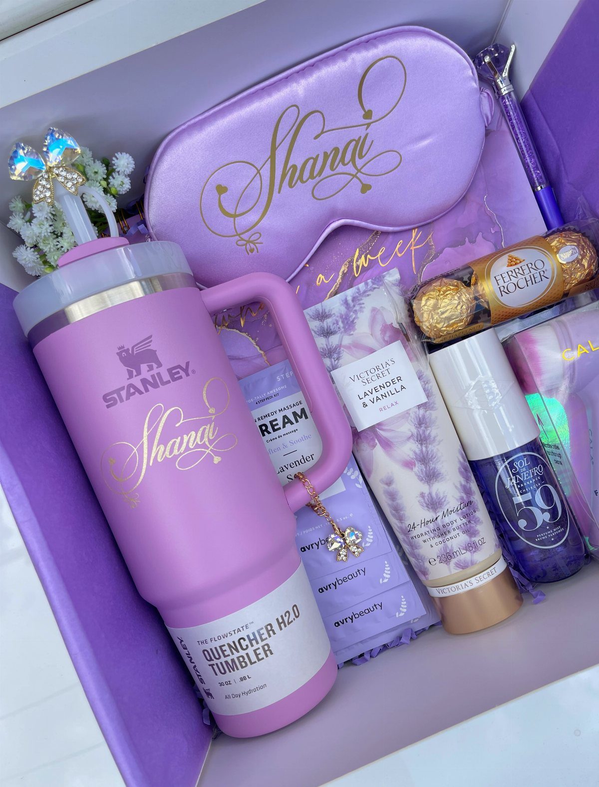 Purple gift box with a Stanley tumbler, sleep mask, and beauty products.
