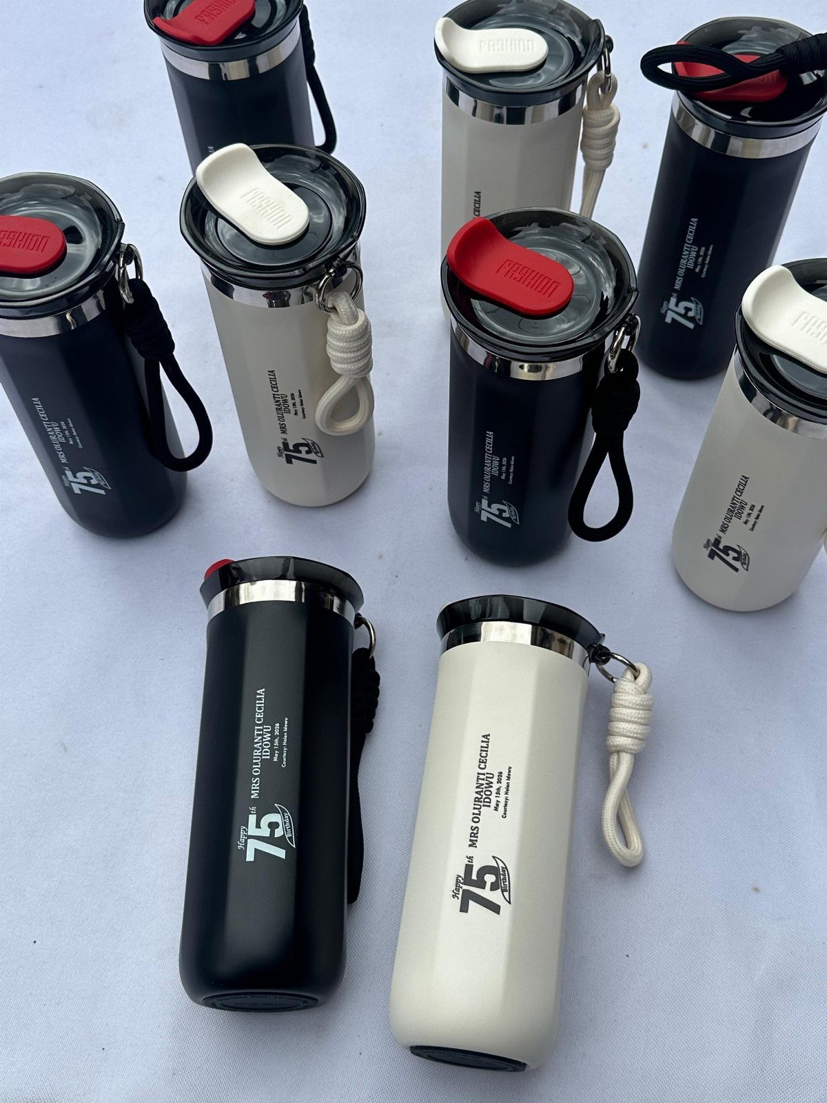 Navy blue and cream travel mugs with lids and straps on white background