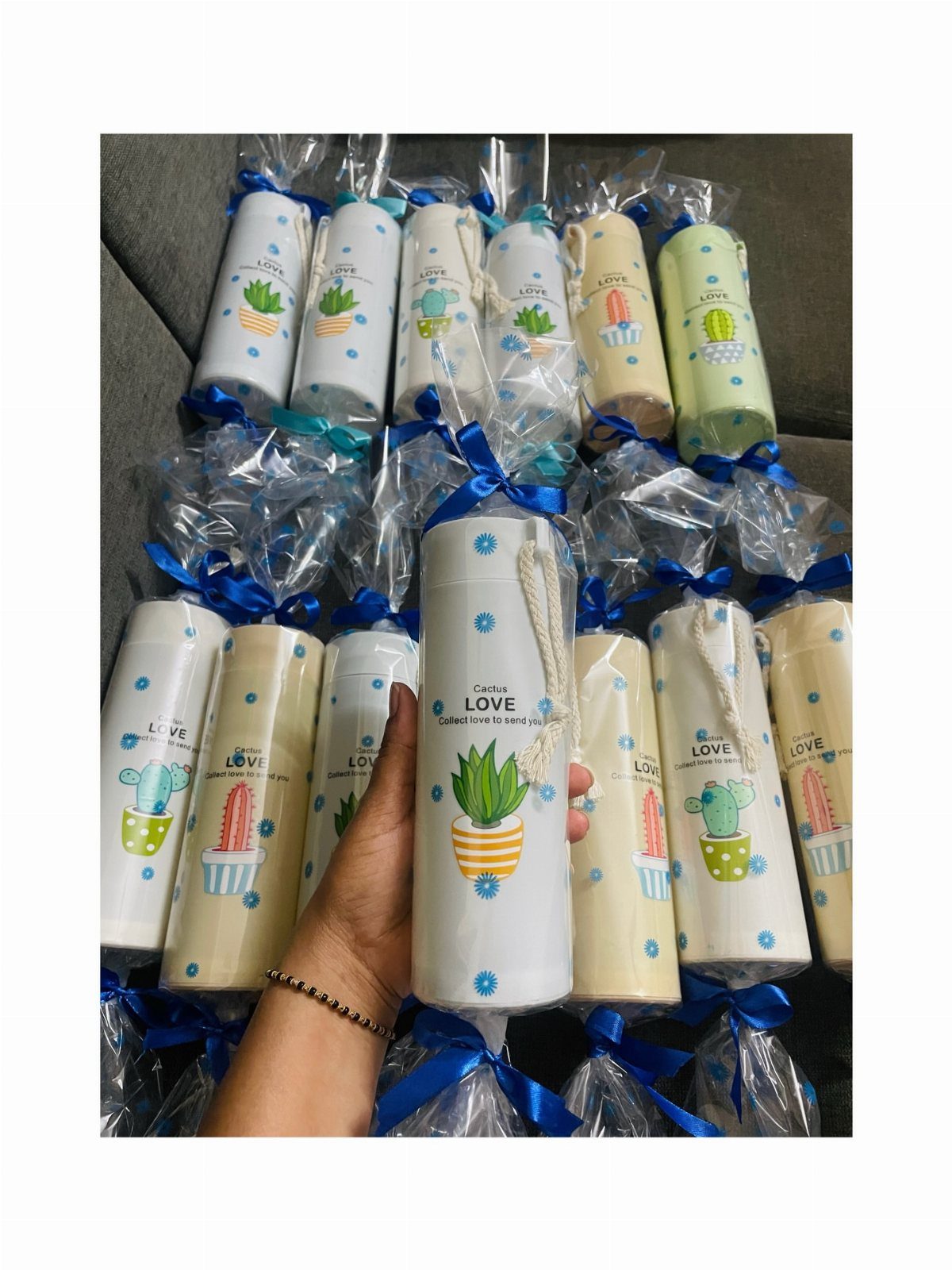 Cactus themed water bottles wrapped in clear cellophane with blue ribbons as gifts.