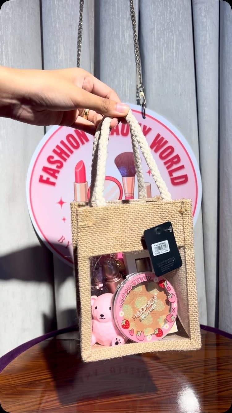 Burlap gift bag with a clear window containing pink beauty products and a bear.