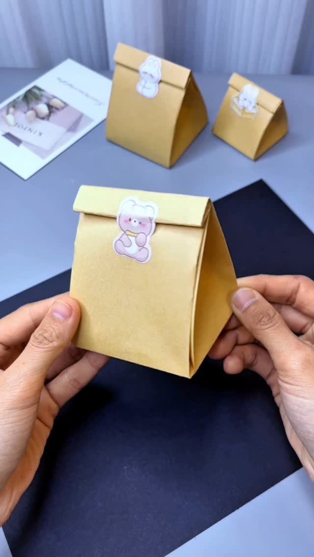 Handmade yellow paper gift bags with cute bear stickers on a grey surface