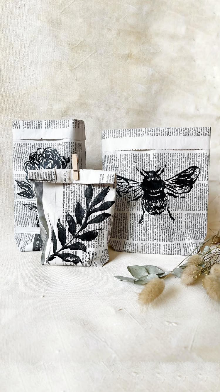 Handmade newspaper gift bags with black ink stamps of a bee and leaves.