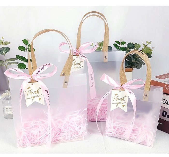 Translucent white gift bags with pink ribbons and thank you tags