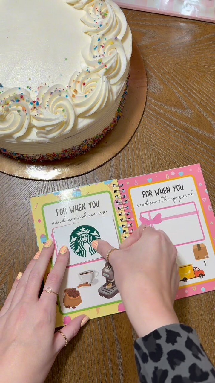 Handmade mini booklet holding a Starbucks gift card next to a frosted cake.