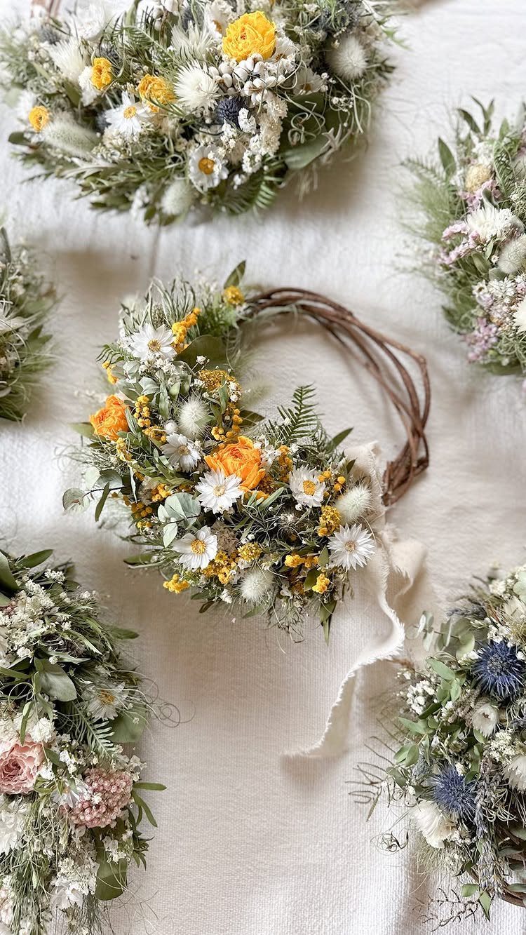 Handmade flower wreaths with dried yellow and white blossoms on a white cloth