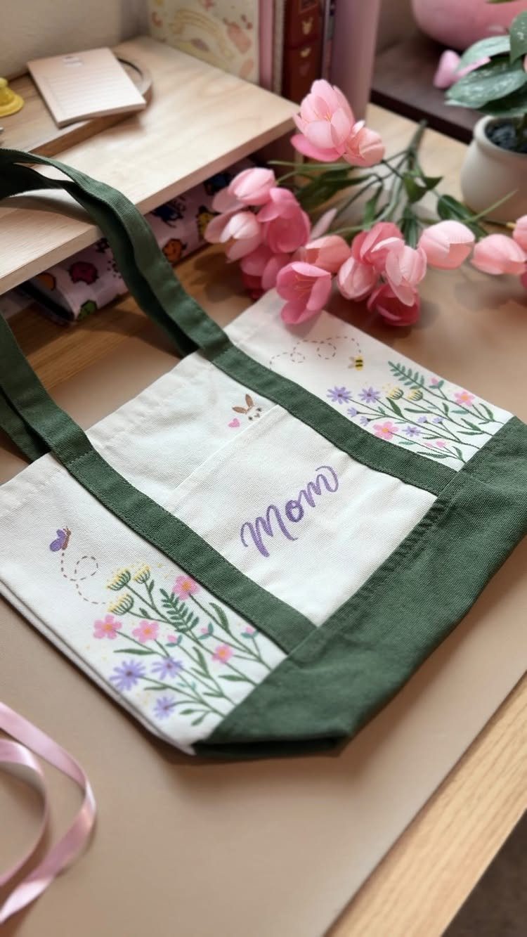 Embroidered white canvas tote bag for Mom with floral patterns and green straps.