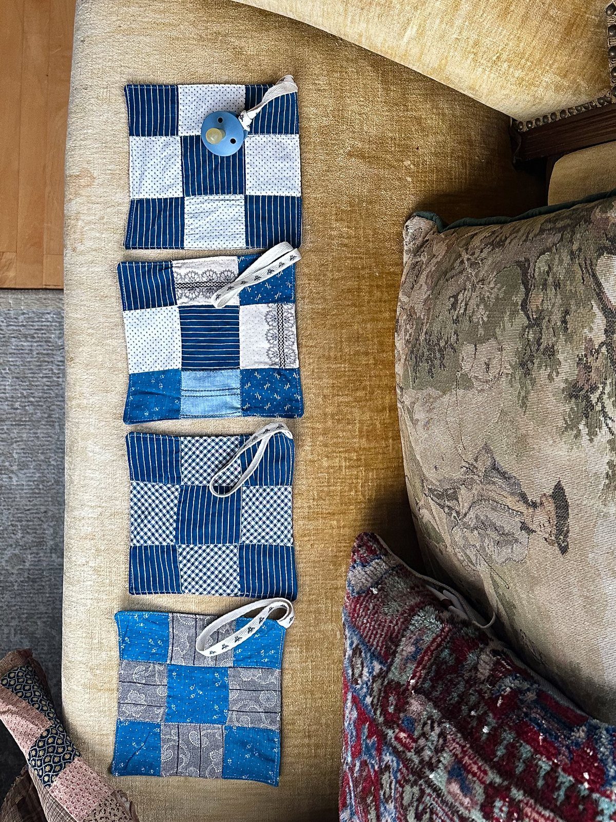 Four blue and white patterned fabric coasters resting on a tan sofa.