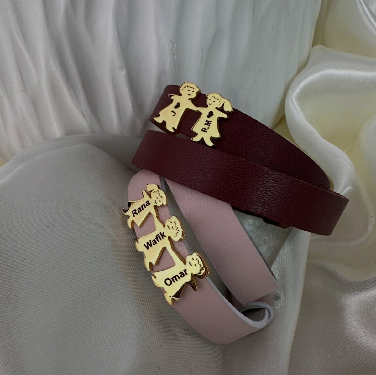 Leather bracelets in burgundy and pink with gold personalized child-shaped name charms.