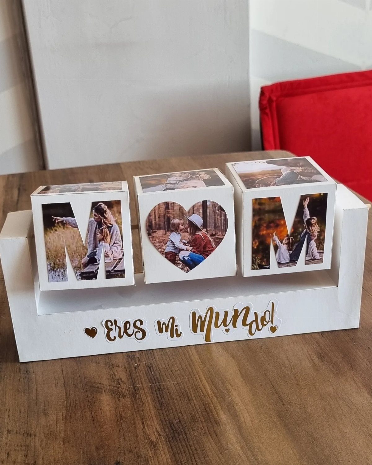 Three white photo cubes spelling MOM in a wooden holder on a table