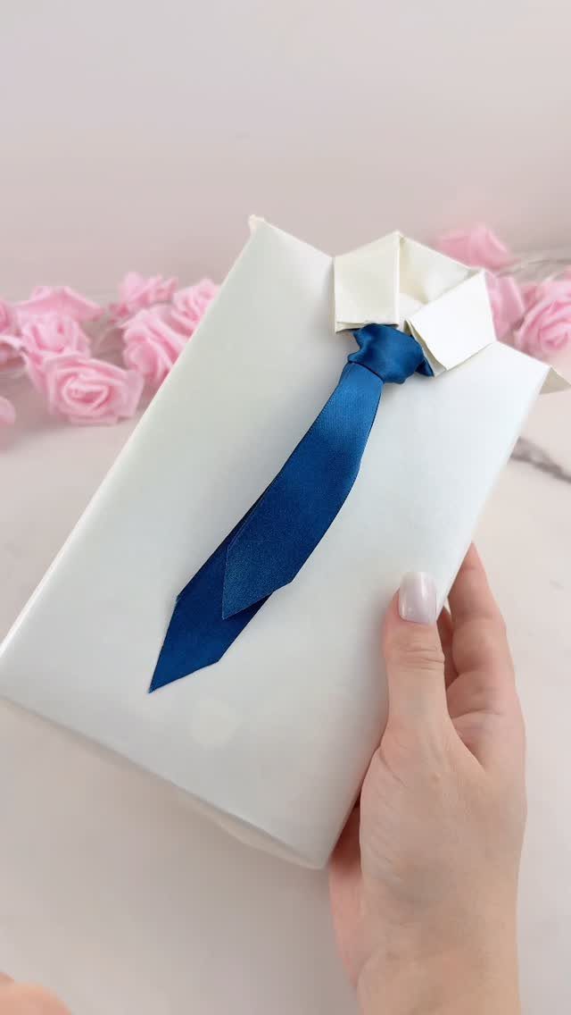 White wrapped gift designed as a shirt with a blue ribbon necktie