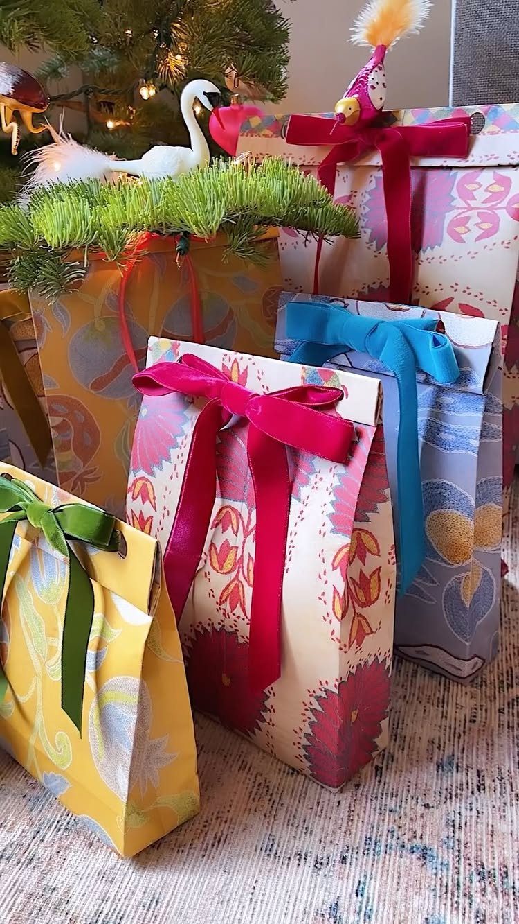 Handmade gift bags made from colorful patterned wrapping paper tied with satin ribbons.