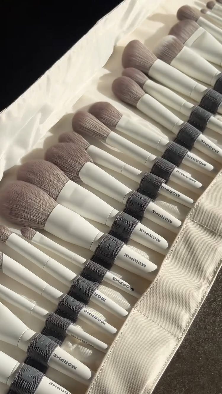 Makeup brushes with white handles and grey bristles in a white organizer case