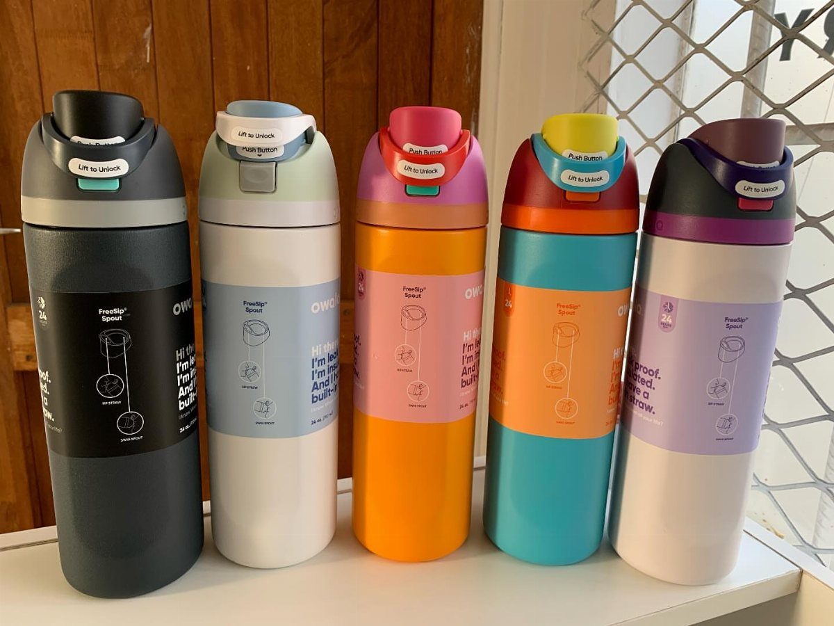 Five colorful Owala FreeSip water bottles lined up on a white shelf.