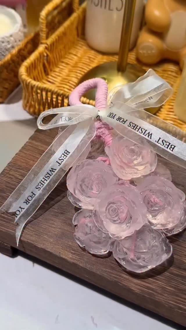 Pink resin rose bouquet with a white ribbon on a wooden surface