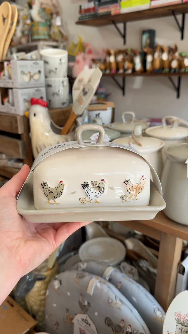 Cream ceramic butter dish with chicken illustrations held in a hand.