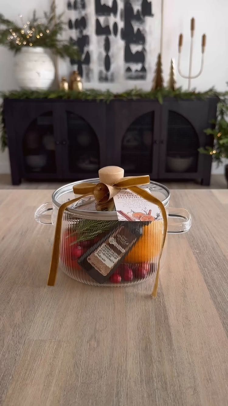 Glass jar filled with dried orange slices and berries tied with gold ribbon.