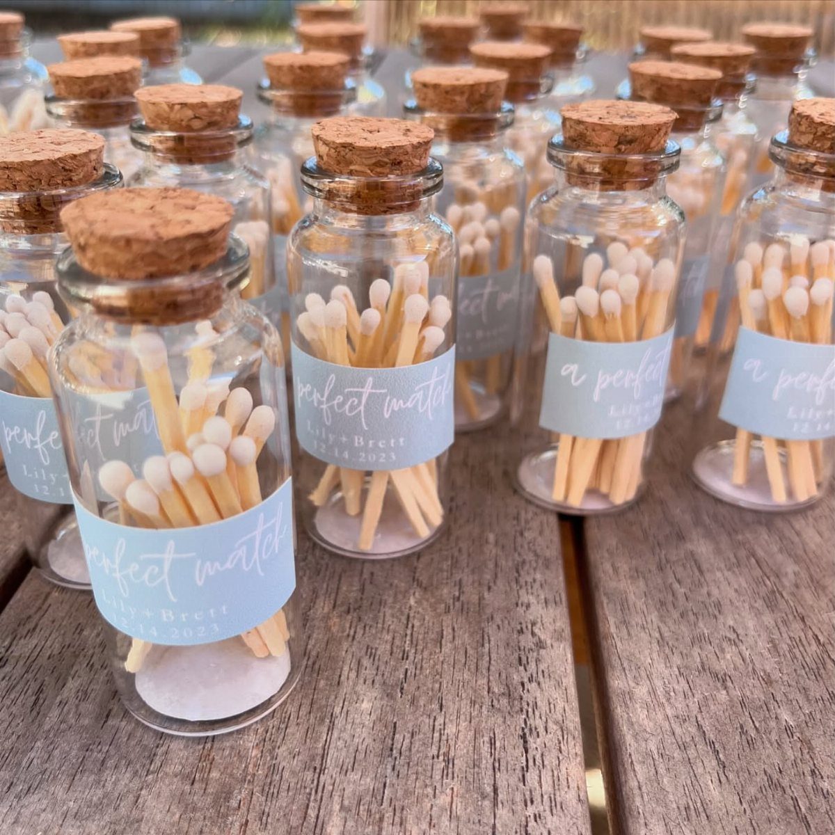 Small glass bottles with cork stoppers filled with matches and blue labels.