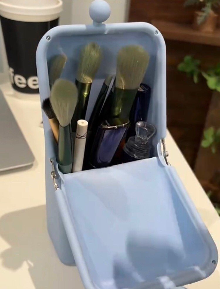Light blue silicone brush holder shaped like a suitcase containing various makeup brushes.