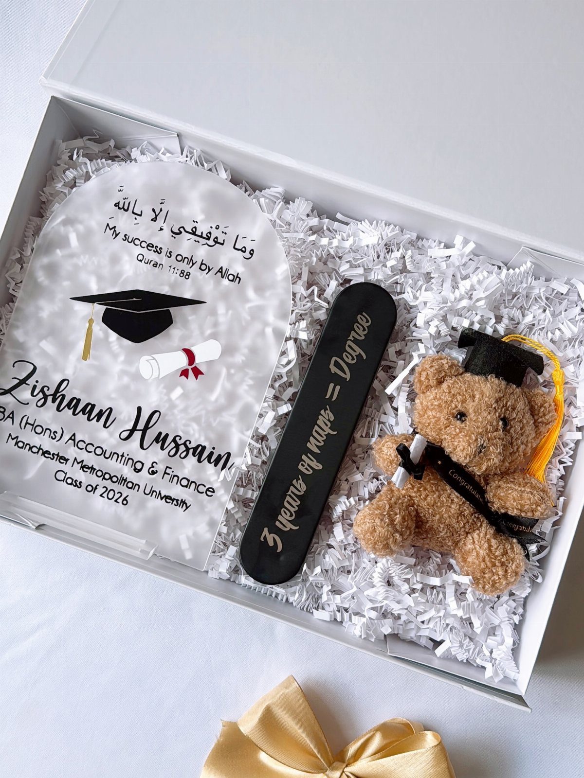 Graduation gift box with personalized acrylic plaque, teddy bear, and shredded paper filler.