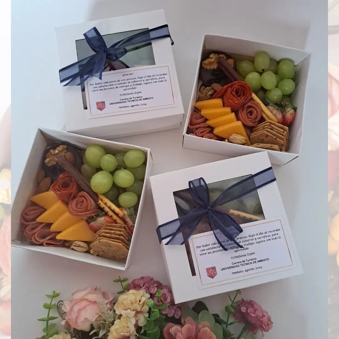 Charcuterie snack boxes with grapes, cheese, and meats, paired with ribboned gift boxes.