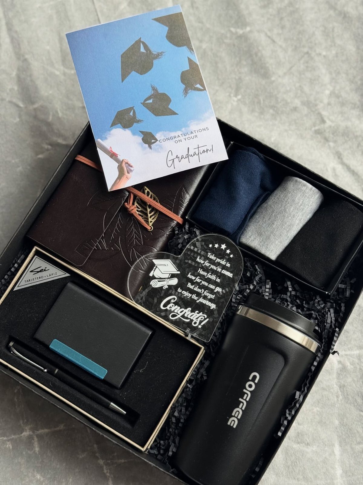 Graduation gift box with coffee mug, notebook, pen, and celebratory graduation card.