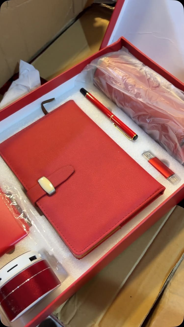 Red gift box filled with a matching notebook, pen, and USB drive.