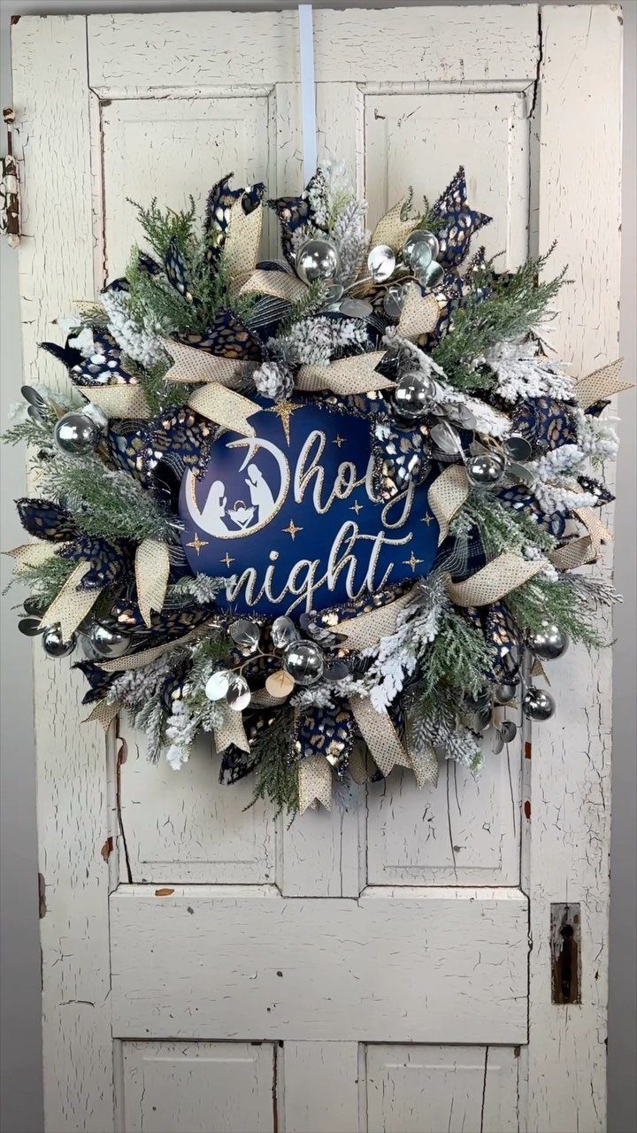 Festive Christmas wreath with silver ornaments and Holy Night sign on white door
