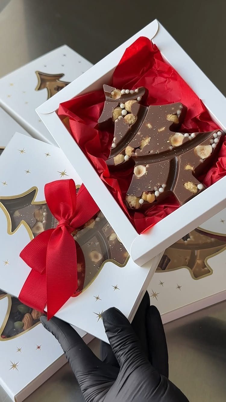 Christmas tree shaped chocolate with nuts in a white gift box with red ribbon