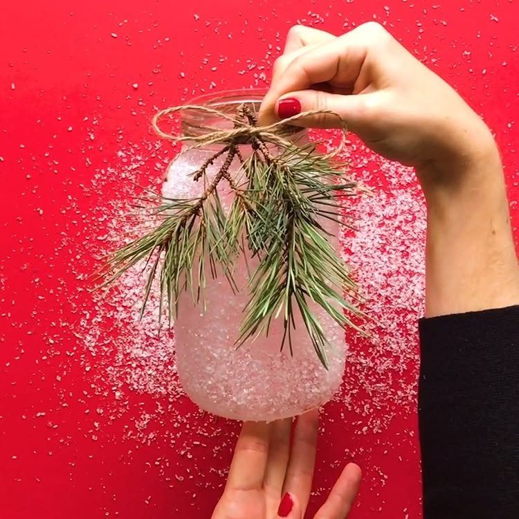 Mason jar filled with white crystals and a pine sprig on red background