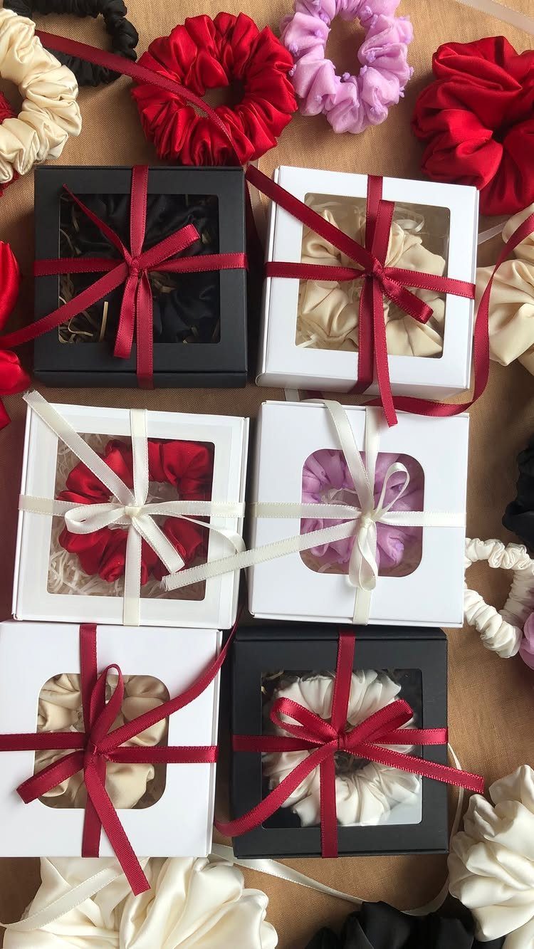Colorful fabric scrunchies displayed loose and packaged in small gift boxes with ribbons.