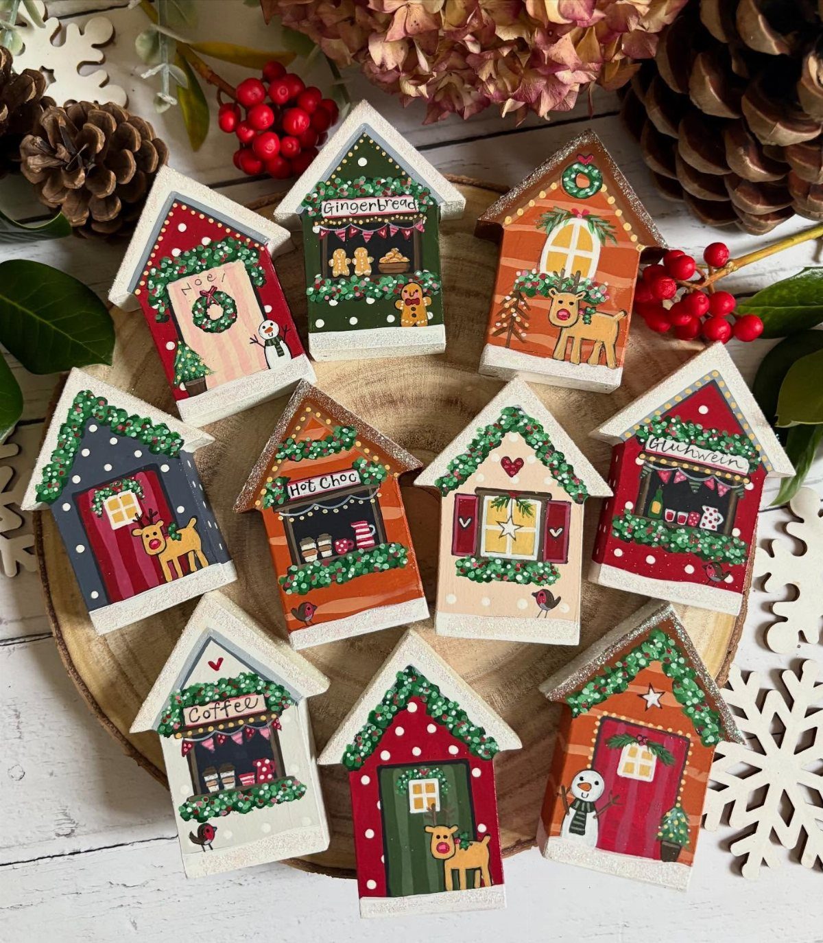 Small colorful wooden house decorations arranged on a platter with festive holiday accents.