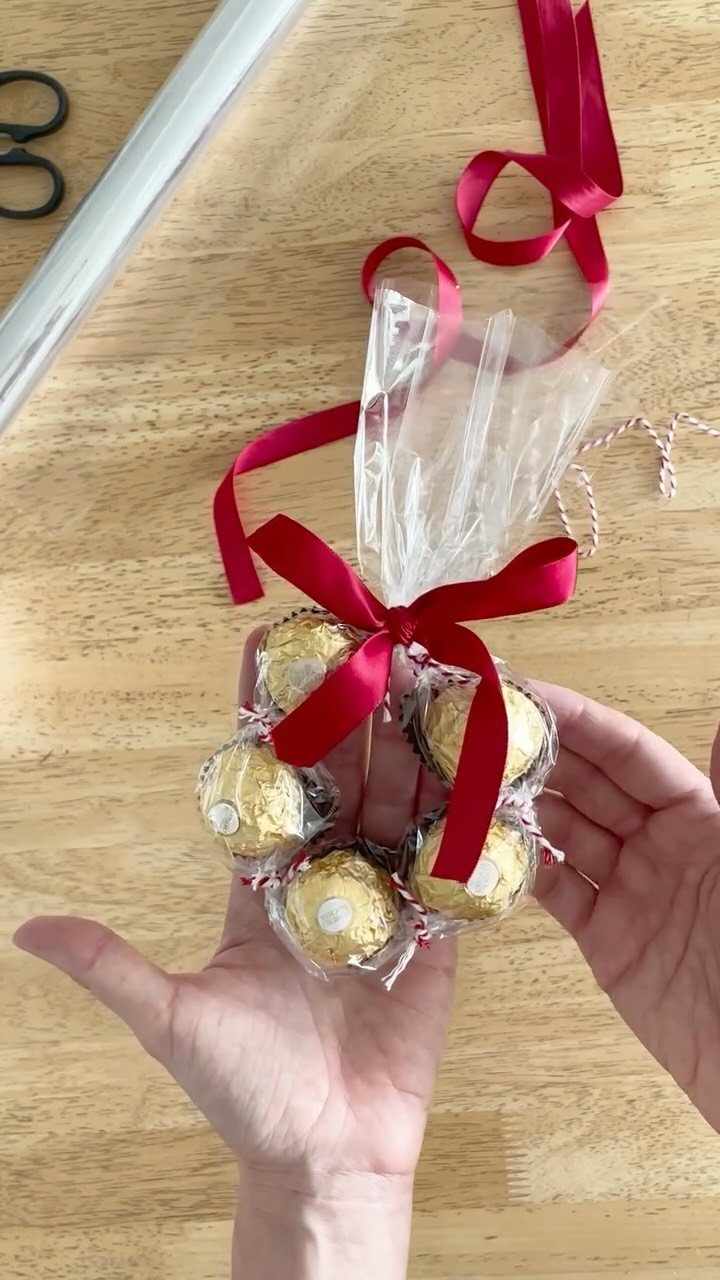 Small chocolate wreath tied with a red ribbon held in two hands.