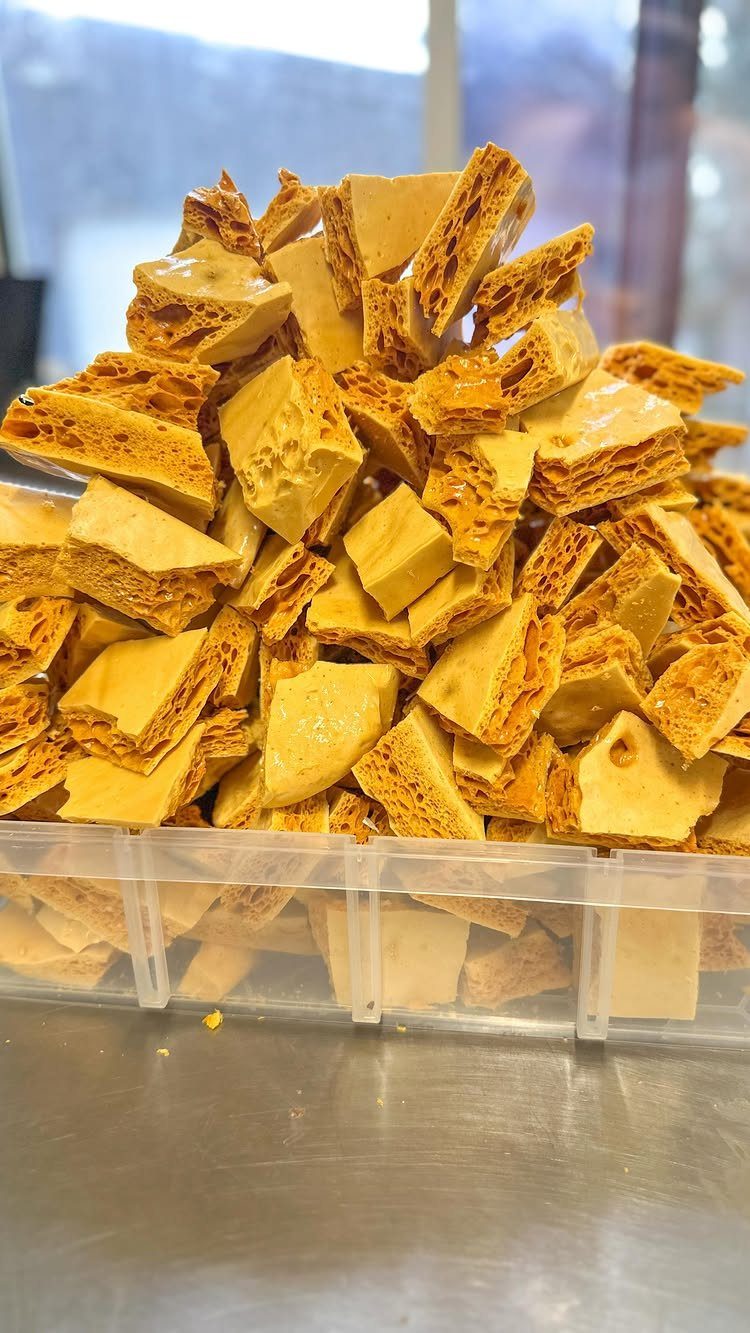 Golden-brown honeycomb candy pieces piled high in a clear plastic container.