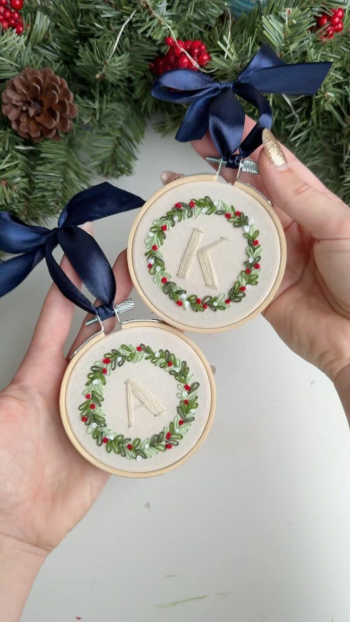 Two small embroidery hoop ornaments with initial letters and festive green wreaths.