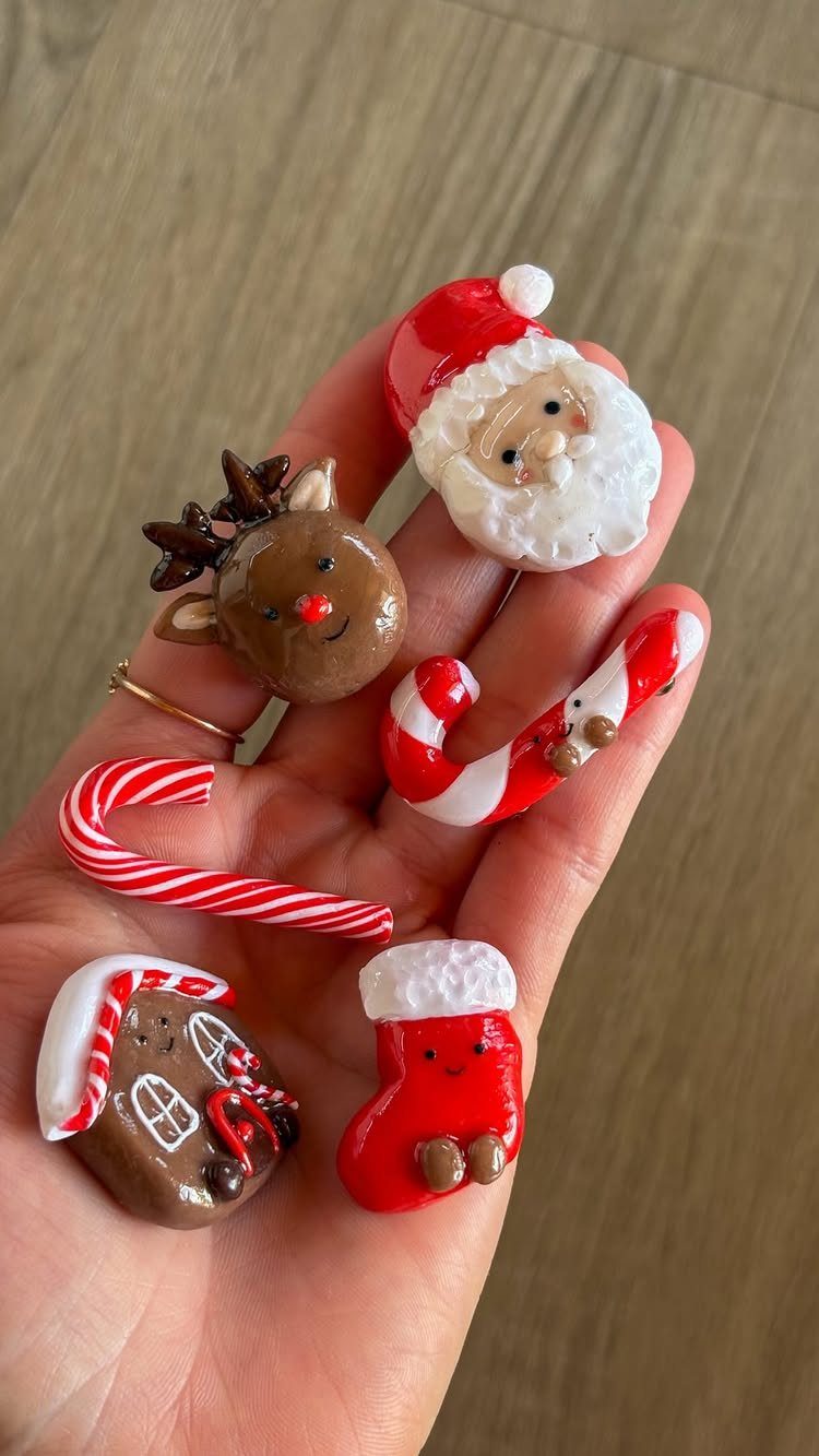Handmade clay Christmas figurines including Santa, reindeer, and candy canes in a palm.