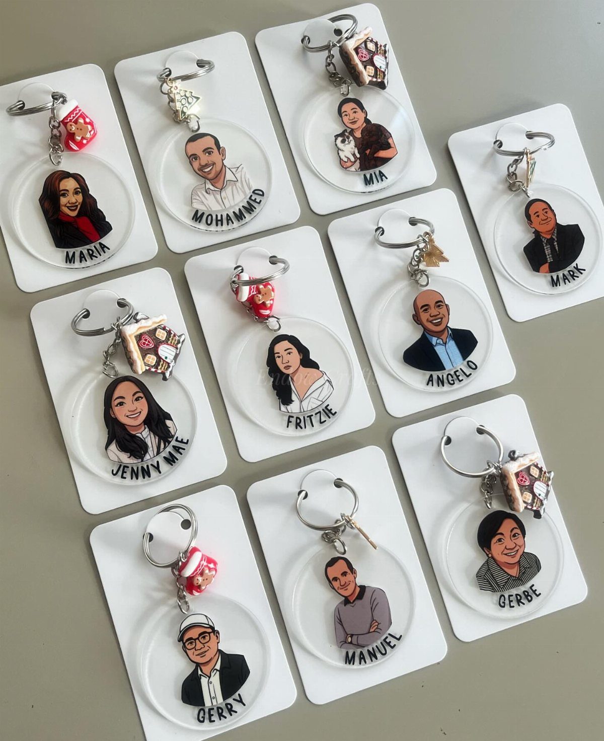 Illustrated portrait keychains with names and charms displayed on white backing cards.