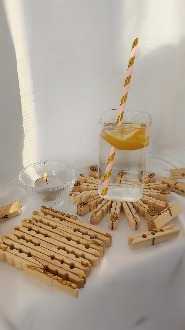 Wooden clothespin coasters holding a glass of water with lemon and a candle.
