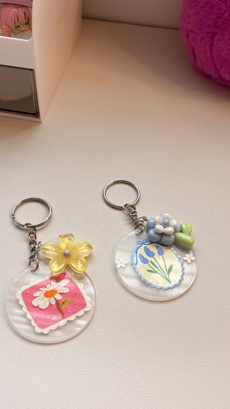 Two handmade acrylic keychains decorated with colorful floral designs and silver rings.