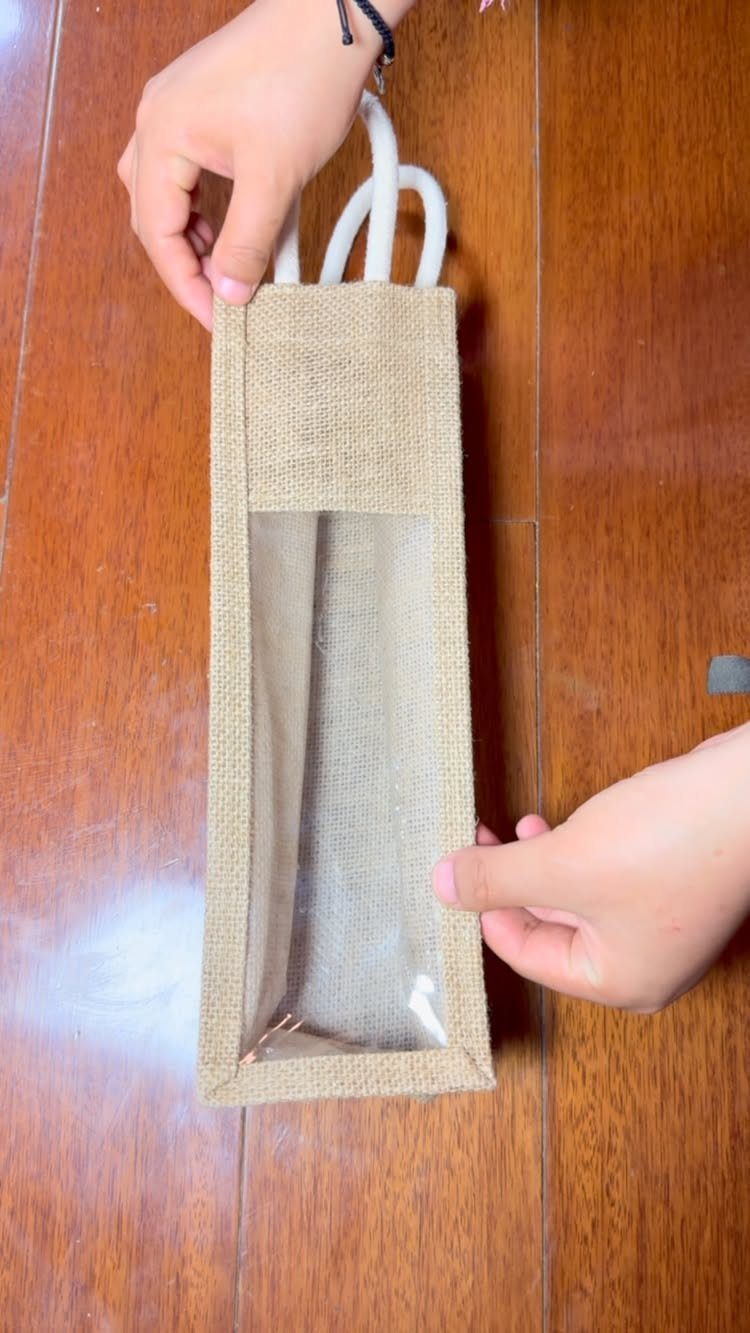 Burlap gift bag with white rope handles and a clear plastic window.