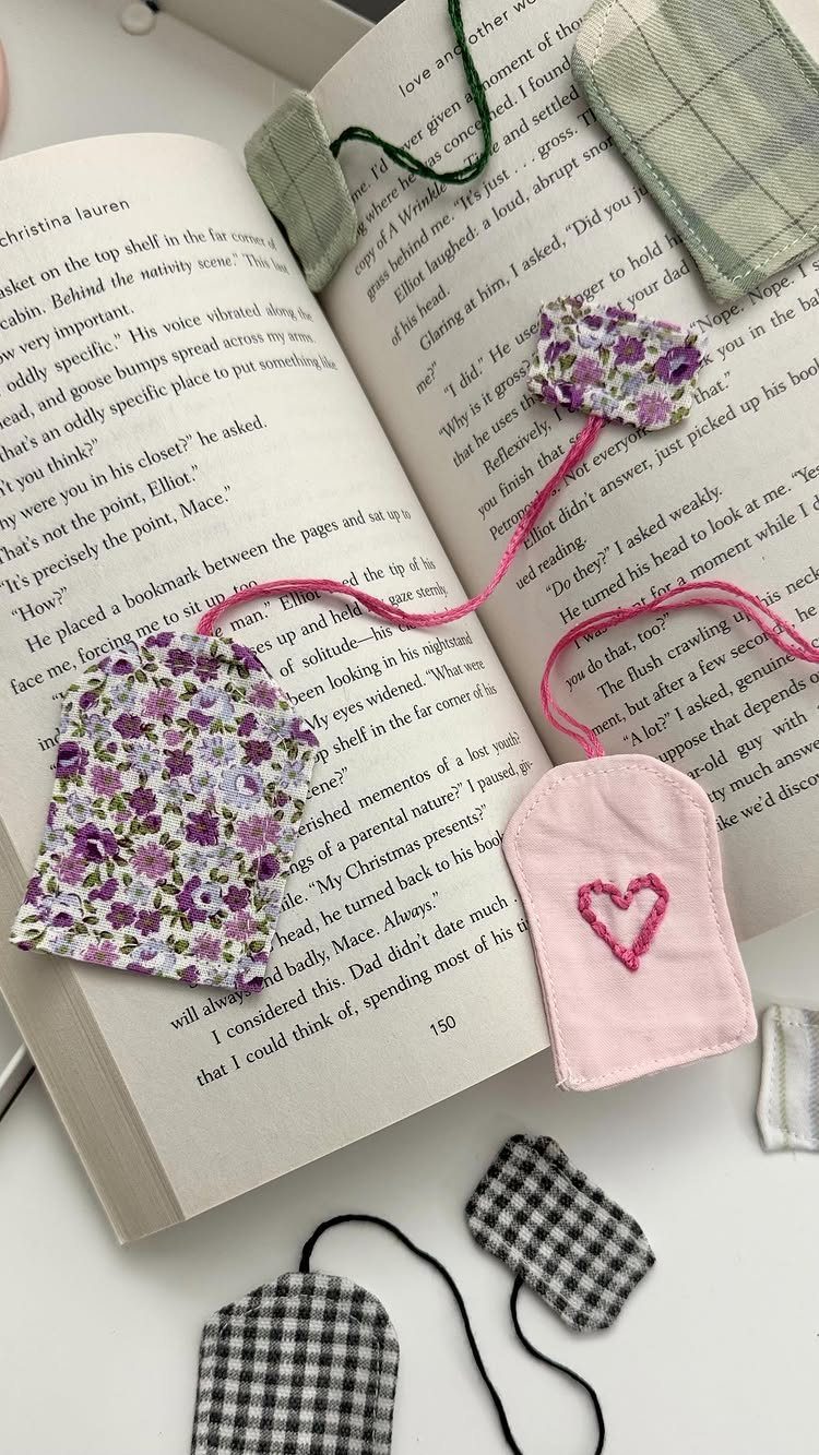 Handmade fabric bookmarks in floral and checkered patterns resting on an open book.